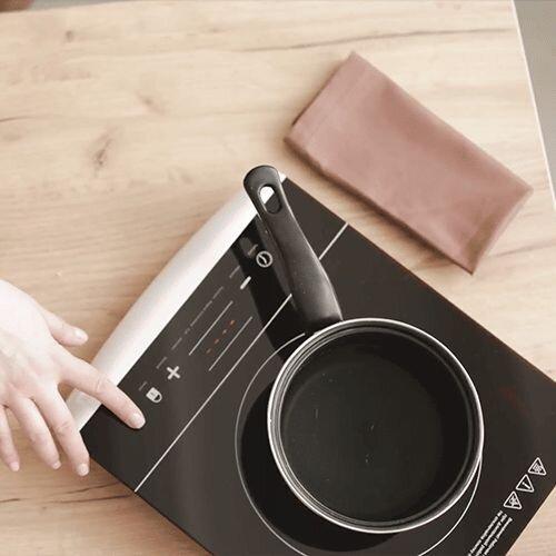 a person using an induction hob on a counter with a pot of water